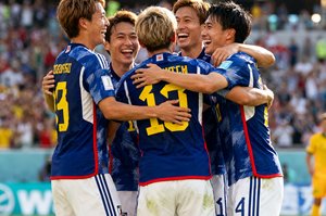 日本队球员在4-1战胜澳大利亚后围在一起庆祝提前出线的场景，球员们笑容满面互相拥抱